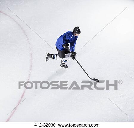 Hockey player in blue uniform skating with puck on ice View Large Photo Image Stock Image - Hockey player in blue uniform skating with puck on ice. Fotosearch