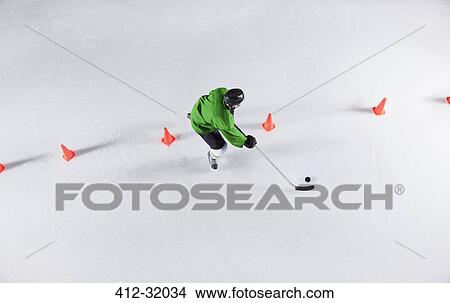 Picture - Hockey player in green uniform doing training drills on ice. Fotosearch