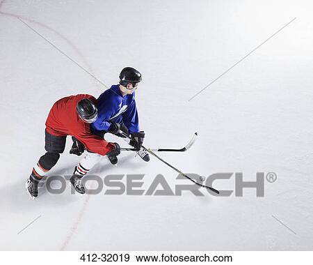 Hockey players going for puck on ice View Large Photo Image Stock Photo - Hockey players going for puck on ice. Fotosearch