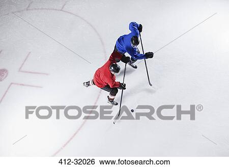 Stock Photograph - Hockey players going for the puck on ice. Fotosearch