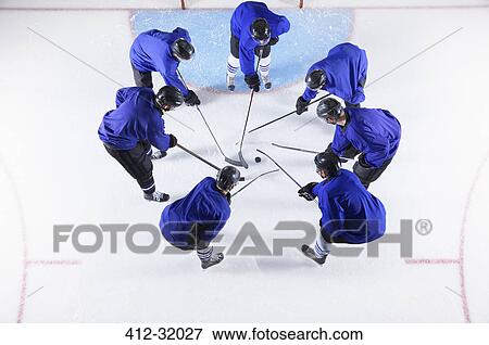 Hockey players in blue uniforms huddling around puck on ice View Large Photo Image Stock Photo - Hockey players in blue uniforms huddling around puck on ice. Fotosearch