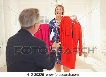 Husband helping wife decide which dress to wear View Large Photo Image Stock Photography - Husband helping wife decide which dress to wear. Fotosearch
