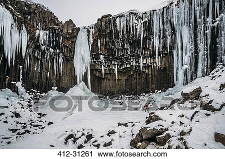 Stock Image - Icicle formations hanging over craggy cliff, Iceland. Fotosearch