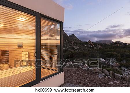 Illuminated home showcase bathroom among craggy landscape at dusk View Large Photo Image Stock Photo - Illuminated home showcase bathroom among craggy landscape at dusk. Fotosearch