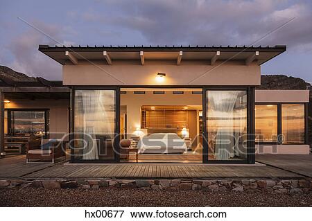 Stock Photo - Illuminated home showcase bedroom with open patio doors. Fotosearch