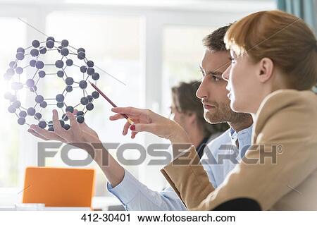 Stock Image - Innovative business people examining model in meeting. Fotosearch