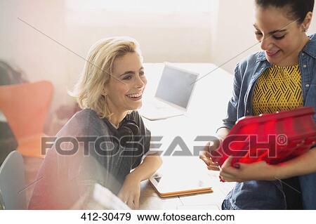 Stock Photo - Innovative young businesswomen examining prototype in office. Fotosearch