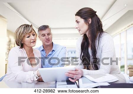 Stock Image - Interior designer using digital tablet in consultation with couple. Fotosearch