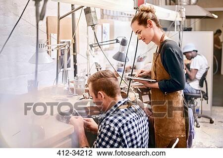 Stock Image - Jeweler and apprentice with digital tablet in workshop. Fotosearch