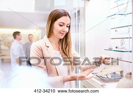 Stock Image - Jeweler arranging display in jewelry store. Fotosearch
