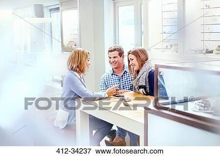 Jeweler helping couple shopping in jewelry store View Large Photo Image Stock Photo - Jeweler helping couple shopping in jewelry store. Fotosearch