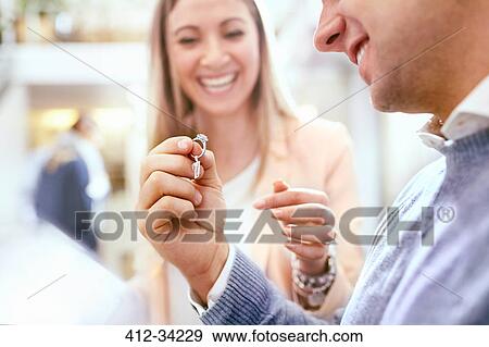Jeweler helping man shopping for diamond ring in jewelry store View Large Photo Image Stock Photo - Jeweler helping man shopping for diamond ring in jewelry store. Fotosearch