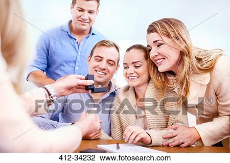 Stock Image - Jeweler showing diamond ring to couples in jewelry store. Fotosearch