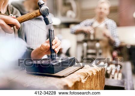 Stock Photo - Jeweler using hammer and equipment in workshop. Fotosearch