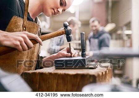 Stock Photography - Jeweler using hammer in workshop. Fotosearch