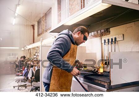 Stock Photograph - Jeweler using torch heating metal in workshop. Fotosearch