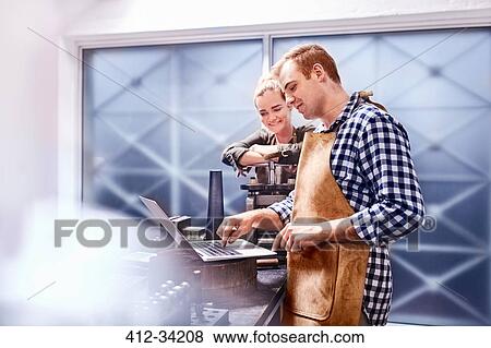 Jewelers using equipment and laptop in workshop View Large Photo Image Stock Photo - Jewelers using equipment and laptop in workshop. Fotosearch