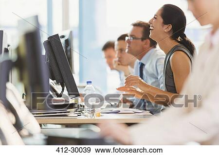 Stock Photo - Laughing businesswoman working at computer in office. Fotosearch
