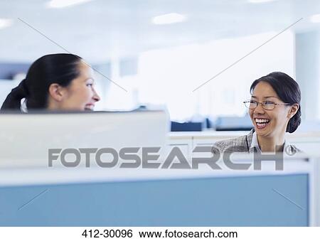 Laughing businesswomen talking in office View Large Photo Image Stock Photograph - Laughing businesswomen talking in office. Fotosearch