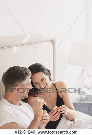 Laughing couple eating in bed View Large Photo Image Stock Image - Laughing couple eating in bed. Fotosearch