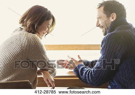 Laughing couple in sweaters at table View Large Photo Image Stock Photography - Laughing couple in sweaters at table. Fotosearch