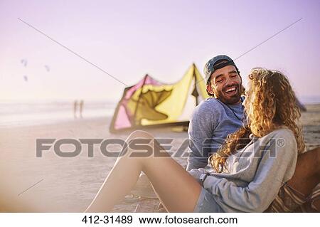 Laughing couple relaxing on sunny beach View Large Photo Image Stock Photo - Laughing couple relaxing on sunny beach. Fotosearch