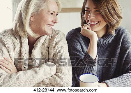 Laughing mother and daughter in sweaters drinking coffee View Large Photo Image Picture - Laughing mother and daughter in sweaters drinking coffee. Fotosearch
