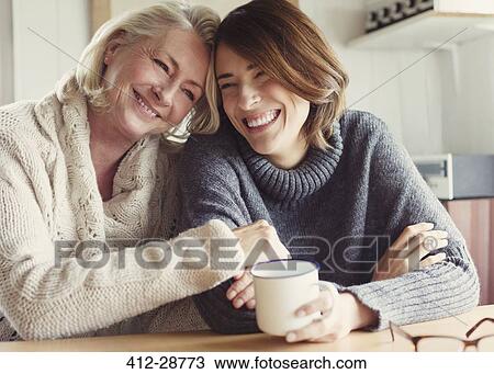 Laughing mother and daughter in sweaters hugging and drinking coffee View Large Photo Image Stock Image - Laughing mother and daughter in sweaters hugging and drinking coffee. Fotosearch
