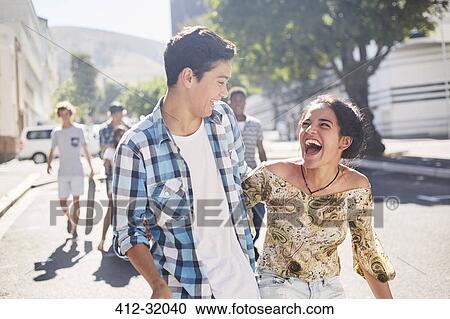 Laughing teenage couple on sunny urban street View Large Photo Image Stock Image - Laughing teenage couple on sunny urban street. Fotosearch