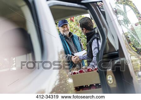 Male farmer and customer handshaking at truck in apple orchard View Large Photo Image Stock Photo - Male farmer and customer handshaking at truck in apple orchard. Fotosearch