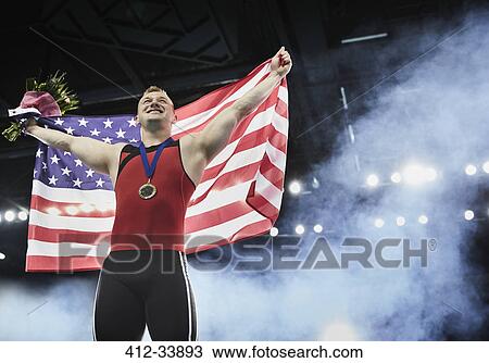 Male gymnast celebrating victory holding American flag on winners podium View Large Photo Image Stock Image - Male gymnast celebrating victory holding American flag on winners podium. Fotosearch