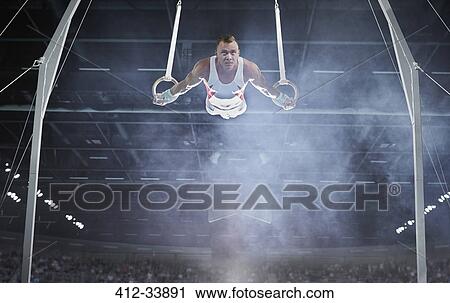 Male gymnast performing on gymnastics rings in arena View Large Photo Image Stock Image - Male gymnast performing on gymnastics rings in arena. Fotosearch