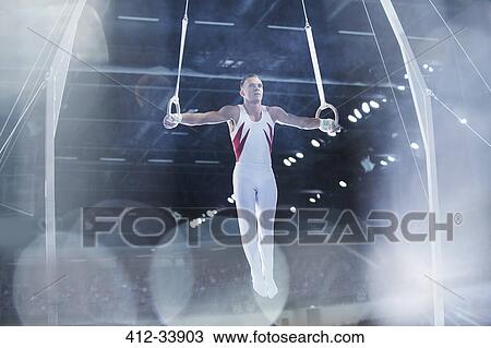 Male gymnast performing on gymnastics rings in arena View Large Photo Image Stock Image - Male gymnast performing on gymnastics rings in arena. Fotosearch