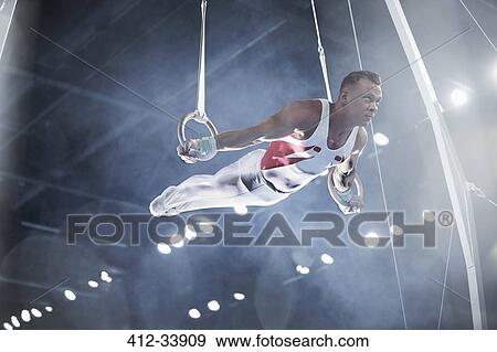 Male gymnast performing on gymnastics rings in arena View Large Photo Image Stock Photo - Male gymnast performing on gymnastics rings in arena. Fotosearch