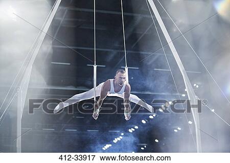 Male gymnast performing on gymnastics rings in arena View Large Photo Image Stock Photo - Male gymnast performing on gymnastics rings in arena. Fotosearch