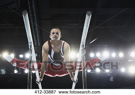 Stock Photo - Male gymnast performing splits on parallel bars. Fotosearch