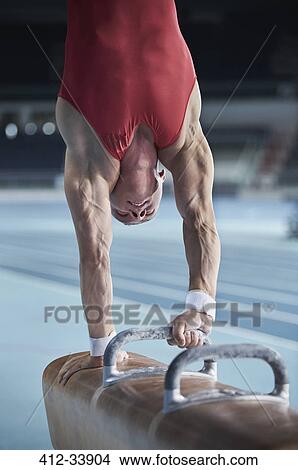Picture - Male gymnast performing upside-down handstand on pommel horse. Fotosearch
