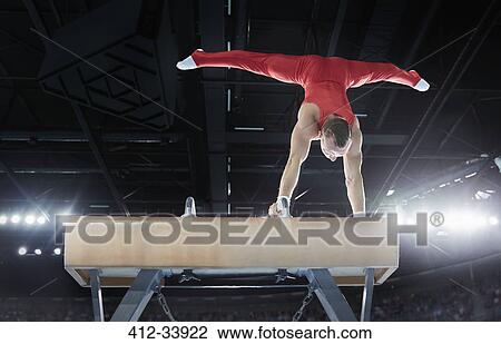 Male gymnast performing upside-down handstand on pommel horse in arena View Large Photo Image Stock Image - Male gymnast performing upside-down handstand on pommel horse in arena. Fotosearch