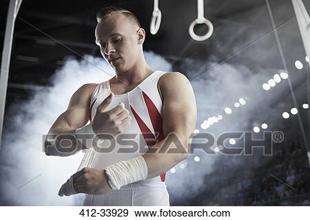 Male gymnast wrapping wrists below gymnastics rings View Large Photo Image Stock Photo - Male gymnast wrapping wrists below gymnastics rings. Fotosearch