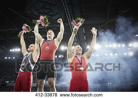 Male gymnasts celebrating victory cheering on winners podium View Large Photo Image Stock Photo - Male gymnasts celebrating victory cheering on winners podium. Fotosearch