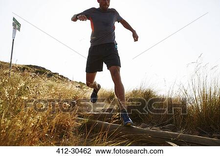Male runner descending trail hillside View Large Photo Image Stock Image - Male runner descending trail hillside. Fotosearch
