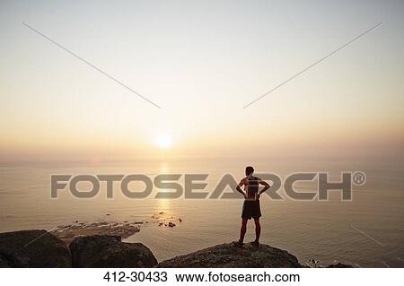 Male runner on rocks looking at sunset ocean view View Large Photo Image Stock Image - Male runner on rocks looking at sunset ocean view. Fotosearch