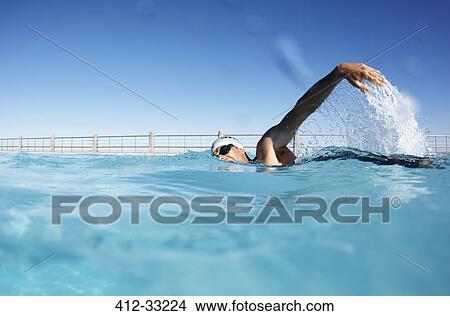 Picture - Male swimmer athlete swimming in sunny swimming pool. Fotosearch