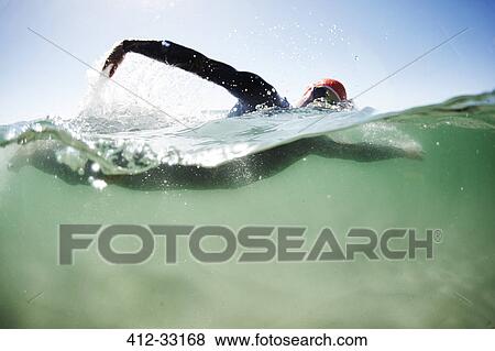 Stock Photo - Male swimmer triathlete swimming in ocean. Fotosearch