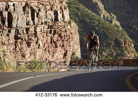 Stock Photograph - Male triathlete cycling uphill. Fotosearch