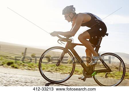 Male triathlete cyclist cycling on sunny rural road at sunrise View Large Photo Image Stock Image - Male triathlete cyclist cycling on sunny rural road at sunrise. Fotosearch