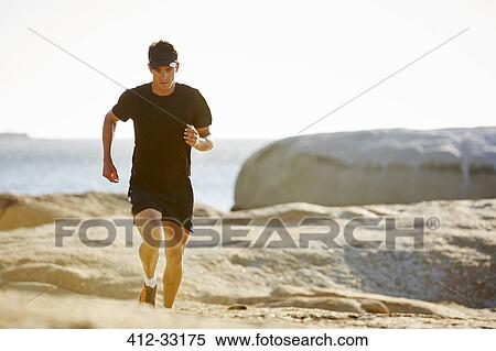 Male triathlete running on sunny rocky trail View Large Photo Image Stock Photography - Male triathlete running on sunny rocky trail. Fotosearch