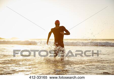 Male triathlete running out of ocean View Large Photo Image Stock Photography - Male triathlete running out of ocean. Fotosearch