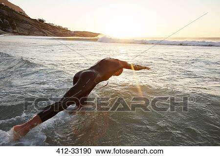 Male triathlete swimmer in wet suit diving into ocean View Large Photo Image Stock Image - Male triathlete swimmer in wet suit diving into ocean. Fotosearch