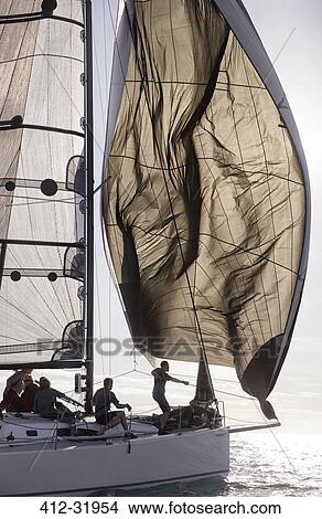 Picture - Man adjusting sail on sailboat. Fotosearch